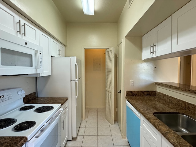 kitchen with white appliances, light tile patterned floors, dark stone counters, and white cabinets