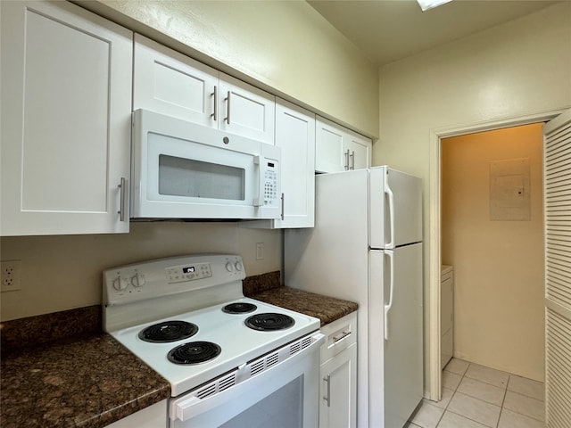 kitchen featuring white appliances, light tile patterned floors, white cabinetry, and dark stone counters