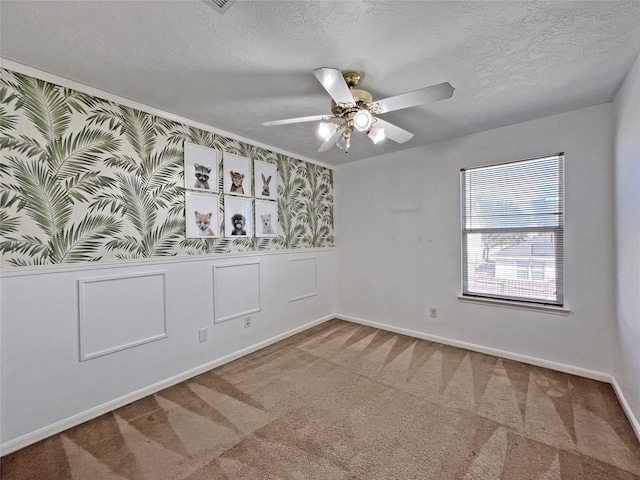 carpeted empty room with ceiling fan and a textured ceiling