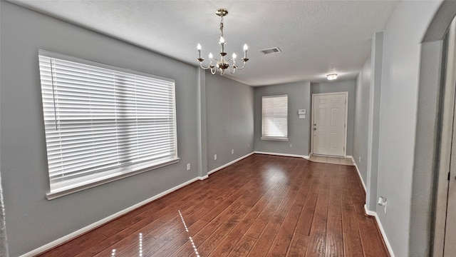 interior space featuring dark wood-type flooring, a textured ceiling, and a notable chandelier