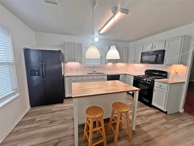 kitchen featuring black appliances, a kitchen bar, sink, and light hardwood / wood-style flooring