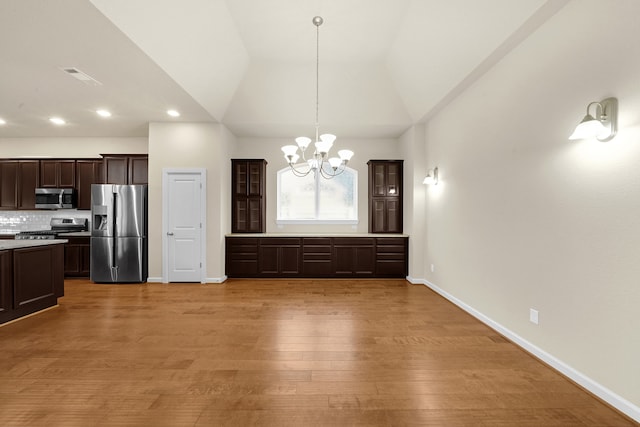 unfurnished dining area with lofted ceiling, a notable chandelier, and light wood-type flooring