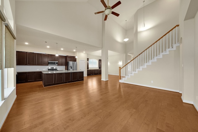 unfurnished living room featuring hardwood / wood-style flooring, high vaulted ceiling, and ceiling fan