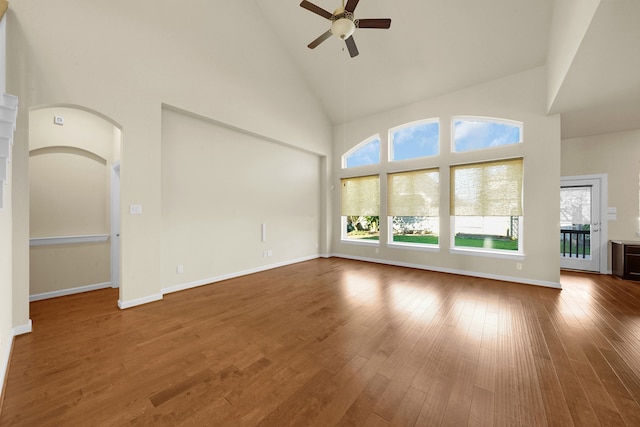 unfurnished living room featuring a wealth of natural light, wood-type flooring, high vaulted ceiling, and ceiling fan