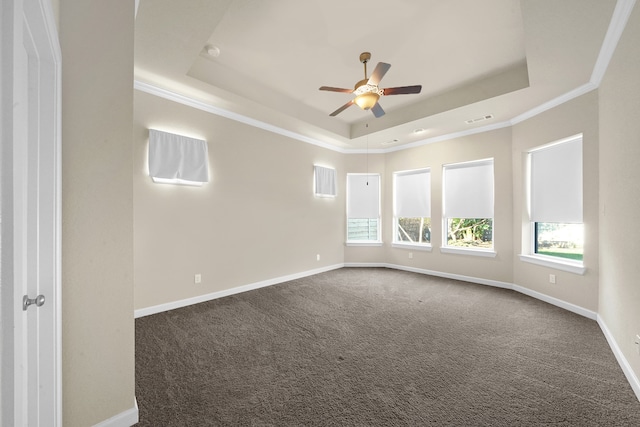 unfurnished room featuring ceiling fan, ornamental molding, a tray ceiling, and dark colored carpet