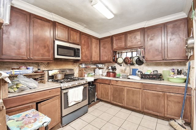 kitchen with sink, appliances with stainless steel finishes, crown molding, and light tile patterned floors