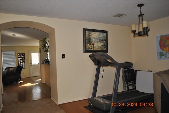 workout area with a notable chandelier and hardwood / wood-style flooring