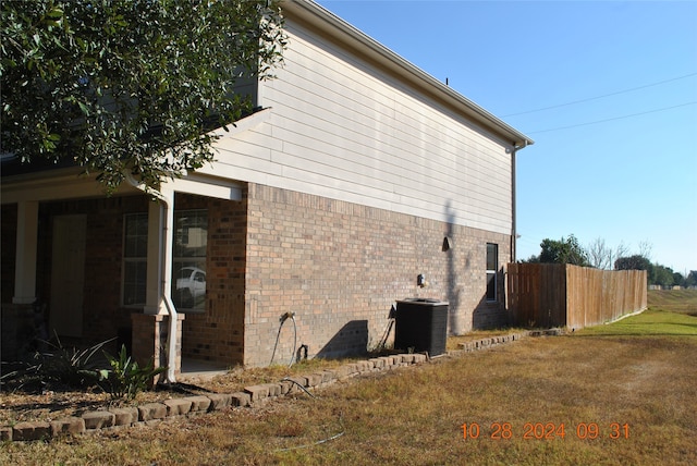 view of side of home with cooling unit and a lawn