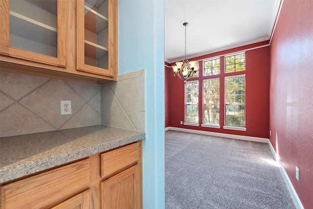 kitchen with an inviting chandelier, crown molding, hanging light fixtures, carpet flooring, and decorative backsplash