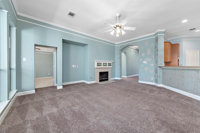 unfurnished living room featuring carpet flooring, ceiling fan, ornamental molding, and a tiled fireplace