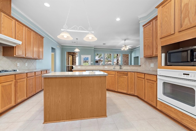 kitchen with tasteful backsplash, kitchen peninsula, crown molding, oven, and a kitchen island