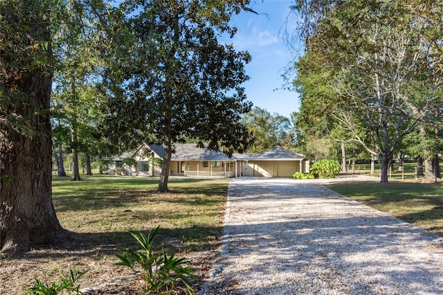 view of front of property featuring an attached carport, a front yard, and gravel driveway