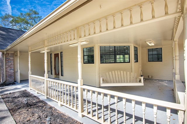 entrance to property with a porch, ceiling fan, and roof with shingles