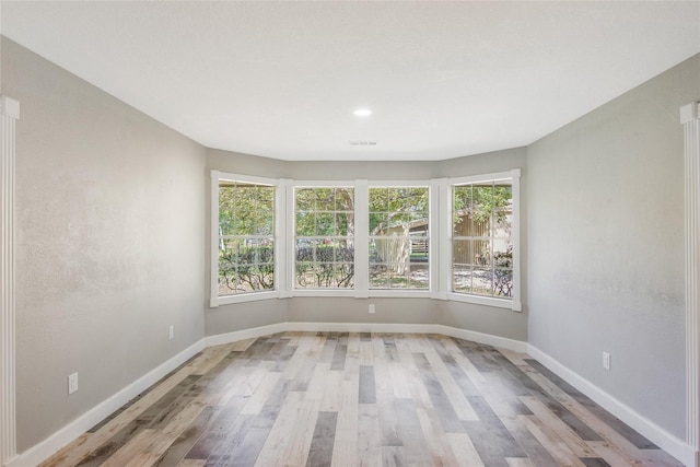 spare room with plenty of natural light, baseboards, wood finished floors, and visible vents