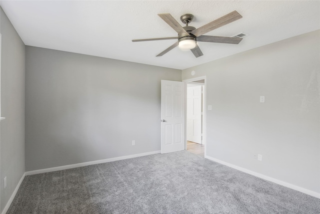 carpeted empty room featuring baseboards, ceiling fan, and visible vents