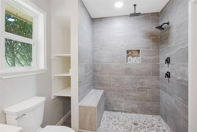 bathroom featuring a tile shower and toilet