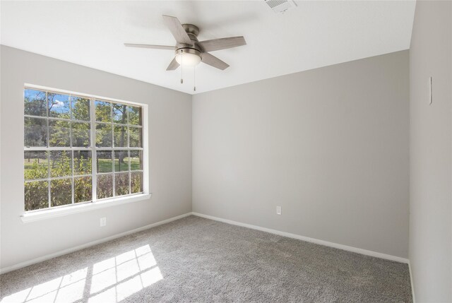 empty room featuring ceiling fan, visible vents, baseboards, and carpet