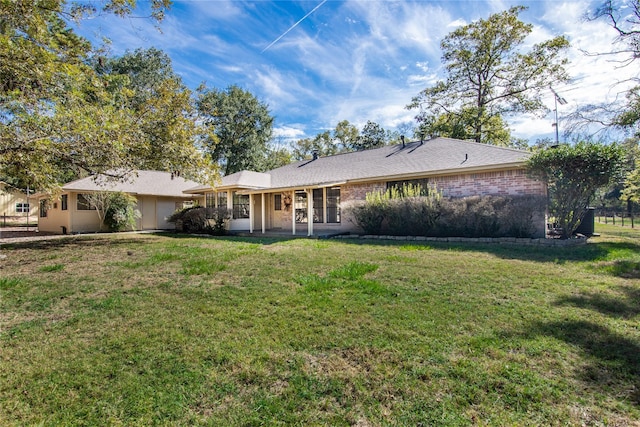 back of house with a yard and brick siding