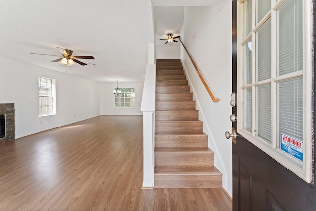 stairway featuring hardwood / wood-style floors and ceiling fan with notable chandelier