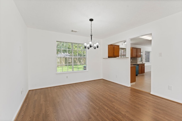 empty room with a chandelier and light hardwood / wood-style floors