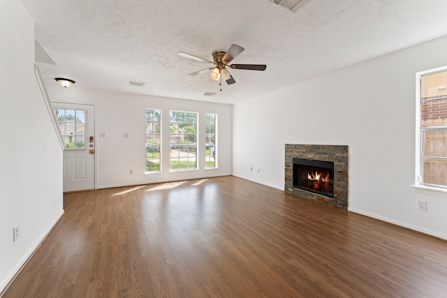 unfurnished living room with dark wood-type flooring, ceiling fan, a healthy amount of sunlight, and a textured ceiling