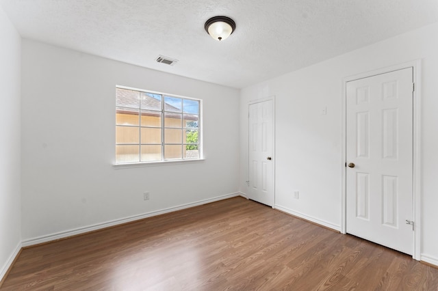 unfurnished room featuring wood-type flooring and a textured ceiling