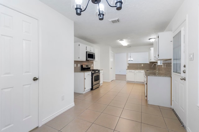 kitchen with stainless steel appliances, light tile patterned flooring, sink, and white cabinets