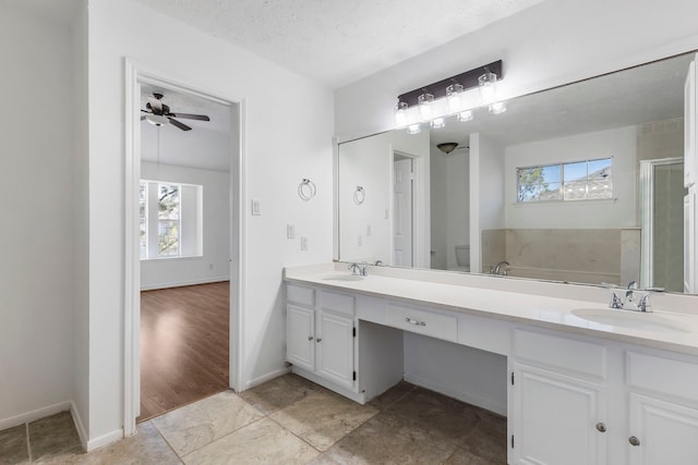 bathroom with ceiling fan, vanity, separate shower and tub, and a textured ceiling