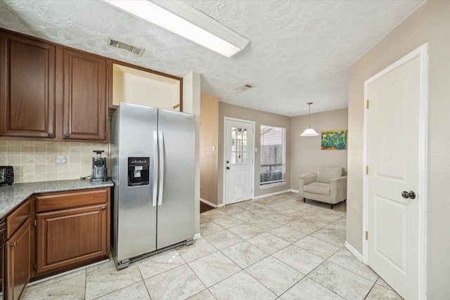 kitchen with decorative backsplash, stainless steel refrigerator with ice dispenser, light tile patterned flooring, pendant lighting, and a textured ceiling