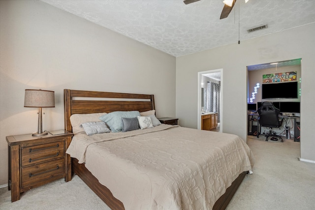 carpeted bedroom featuring a textured ceiling, ensuite bathroom, and ceiling fan