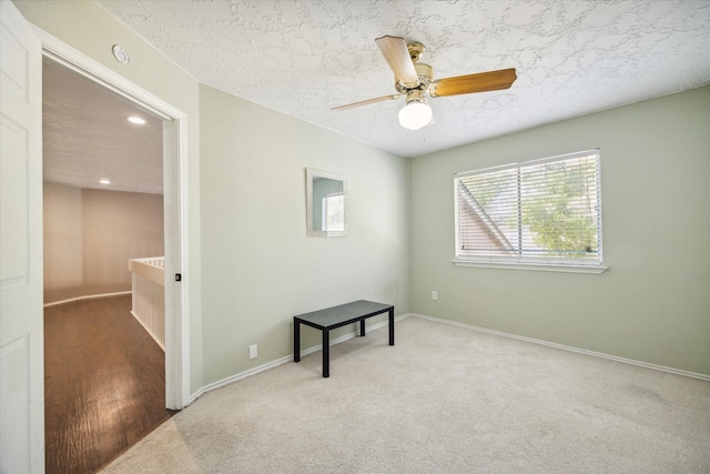 carpeted empty room featuring a textured ceiling and ceiling fan