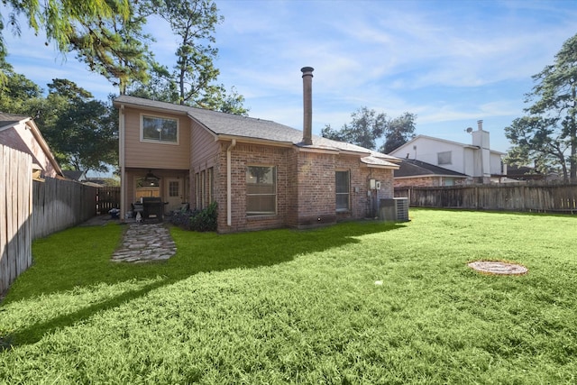 rear view of house with central air condition unit and a lawn