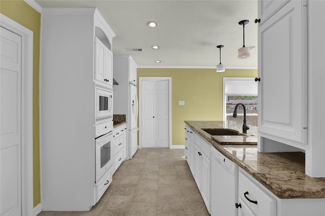 kitchen with white appliances, a sink, visible vents, white cabinets, and hanging light fixtures