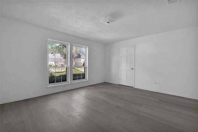 spare room with a textured ceiling and dark hardwood / wood-style floors