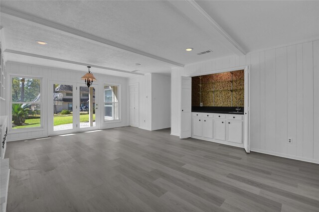 unfurnished living room featuring beam ceiling, a textured ceiling, and wood-type flooring