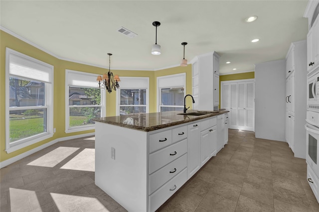 kitchen with white cabinetry, sink, pendant lighting, and a center island with sink