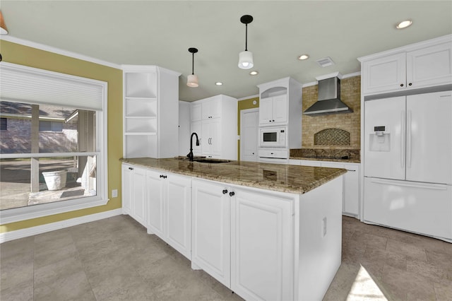 kitchen featuring wall chimney range hood, hanging light fixtures, white cabinetry, sink, and white appliances