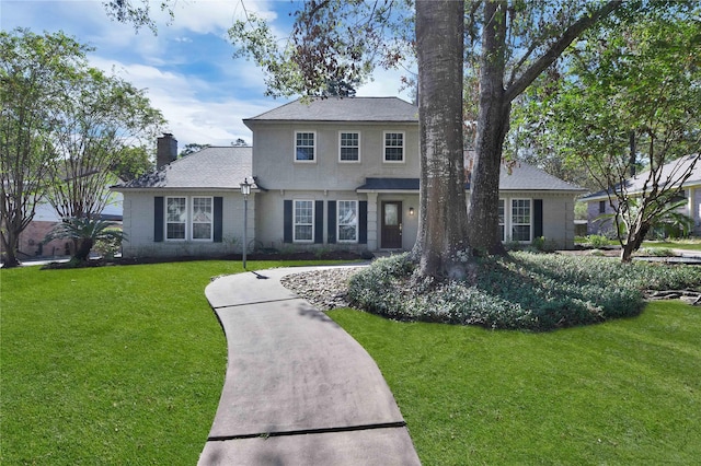 traditional-style home with a front lawn, a chimney, and brick siding