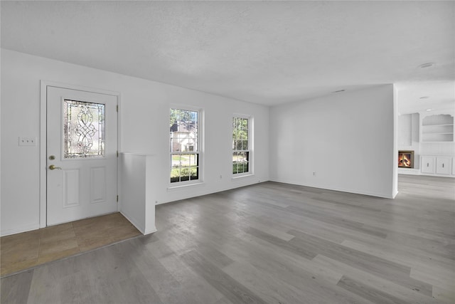 entryway featuring a large fireplace, light wood finished floors, and a textured ceiling