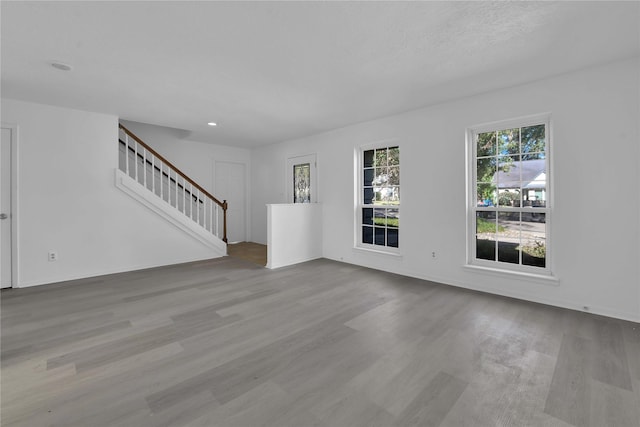 unfurnished living room with light wood-type flooring and stairway