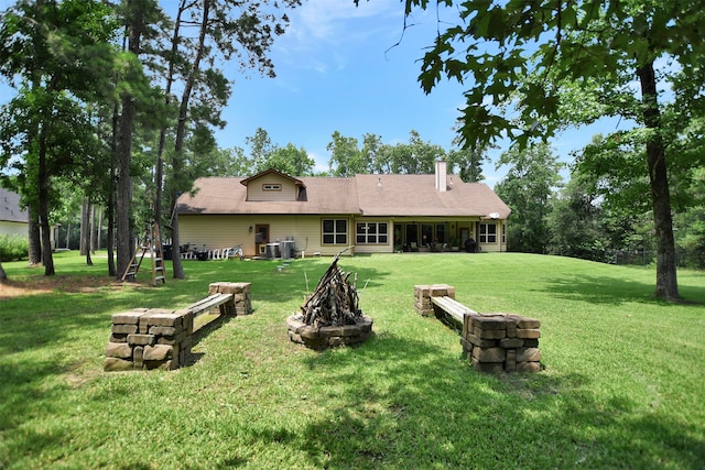 rear view of house with an outdoor fire pit and a lawn