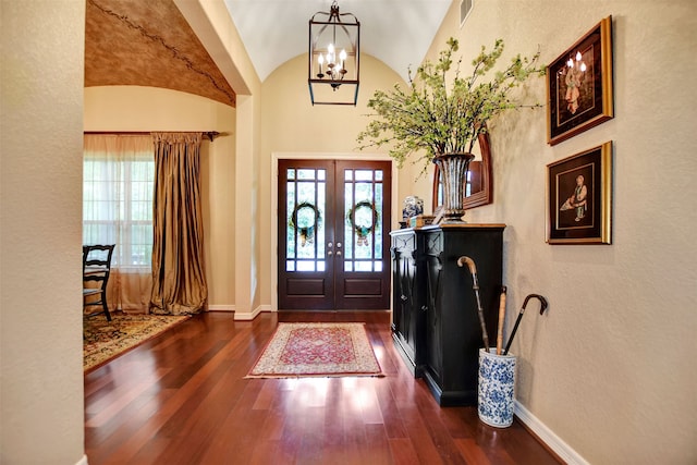 entrance foyer with french doors, dark wood-type flooring, a chandelier, and lofted ceiling