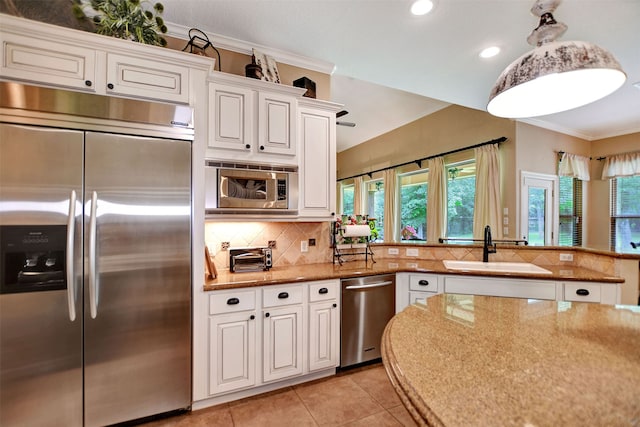 kitchen with built in appliances, ornamental molding, sink, light tile patterned flooring, and white cabinetry