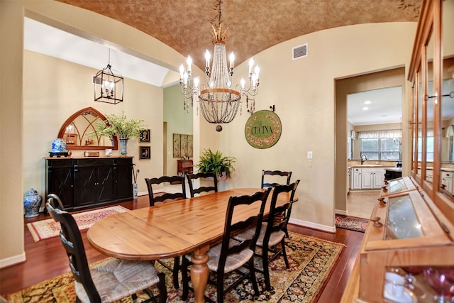 dining room featuring lofted ceiling, wood-type flooring, and an inviting chandelier