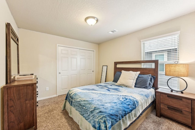 carpeted bedroom featuring a textured ceiling and a closet