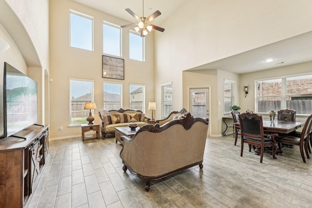 living room featuring ceiling fan and a high ceiling