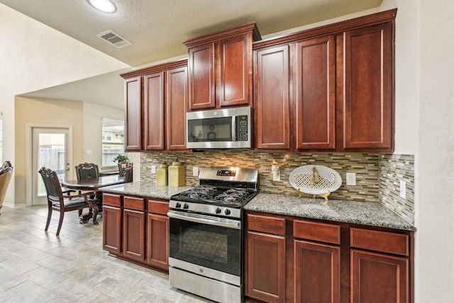 kitchen with a textured ceiling, appliances with stainless steel finishes, backsplash, and light stone counters