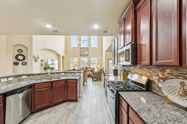 kitchen featuring appliances with stainless steel finishes, sink, backsplash, ceiling fan, and stone counters