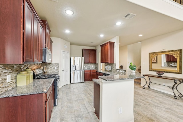 kitchen with stainless steel appliances, decorative backsplash, stone countertops, kitchen peninsula, and light hardwood / wood-style flooring