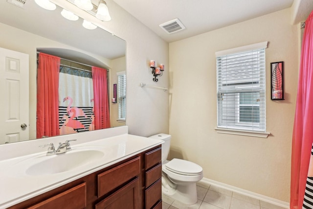 bathroom with toilet, vanity, and tile patterned flooring